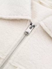 White cropped zip-up jacket with textured fabric and silver zipper detail.