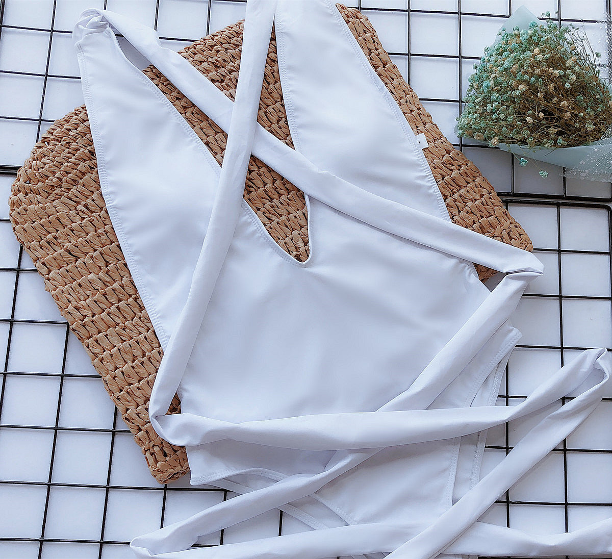 White wrap-around halterneck plunge swimsuit with crisscross back ties.