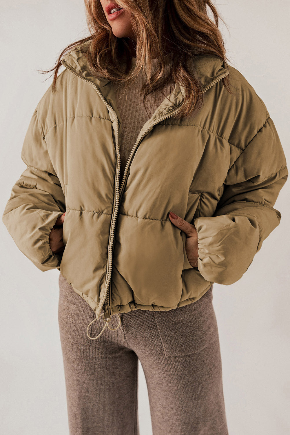 Taupe cropped puffer jacket with hood, zipper front, and drawstring hem.