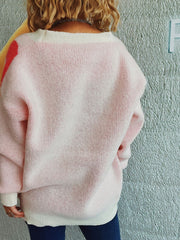 Blush pink acrylic cardigan with cream trim and subtle red floral appliqué detail on shoulder.