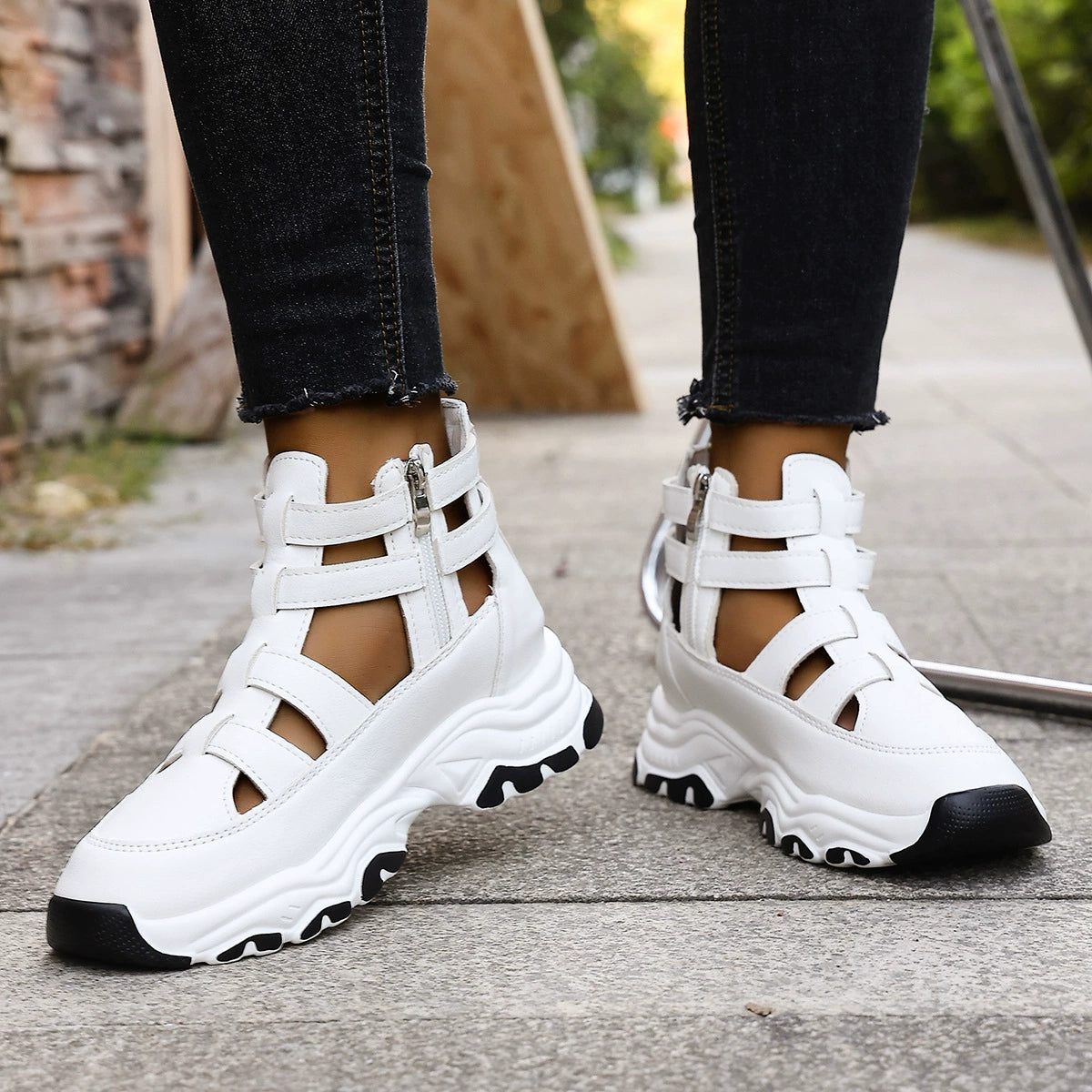 White chunky cutout platform sneakers with ankle straps and zipper detail.