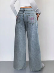 Light wash denim wide-leg jeans with pink embroidered bows on back pockets.