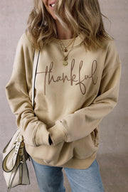 Khaki sweatshirt with "thankful" script graphic and pockets.