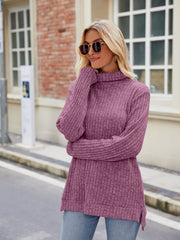 Ribbed turtleneck sweater in Fuchsia with side slits, styled with jeans.