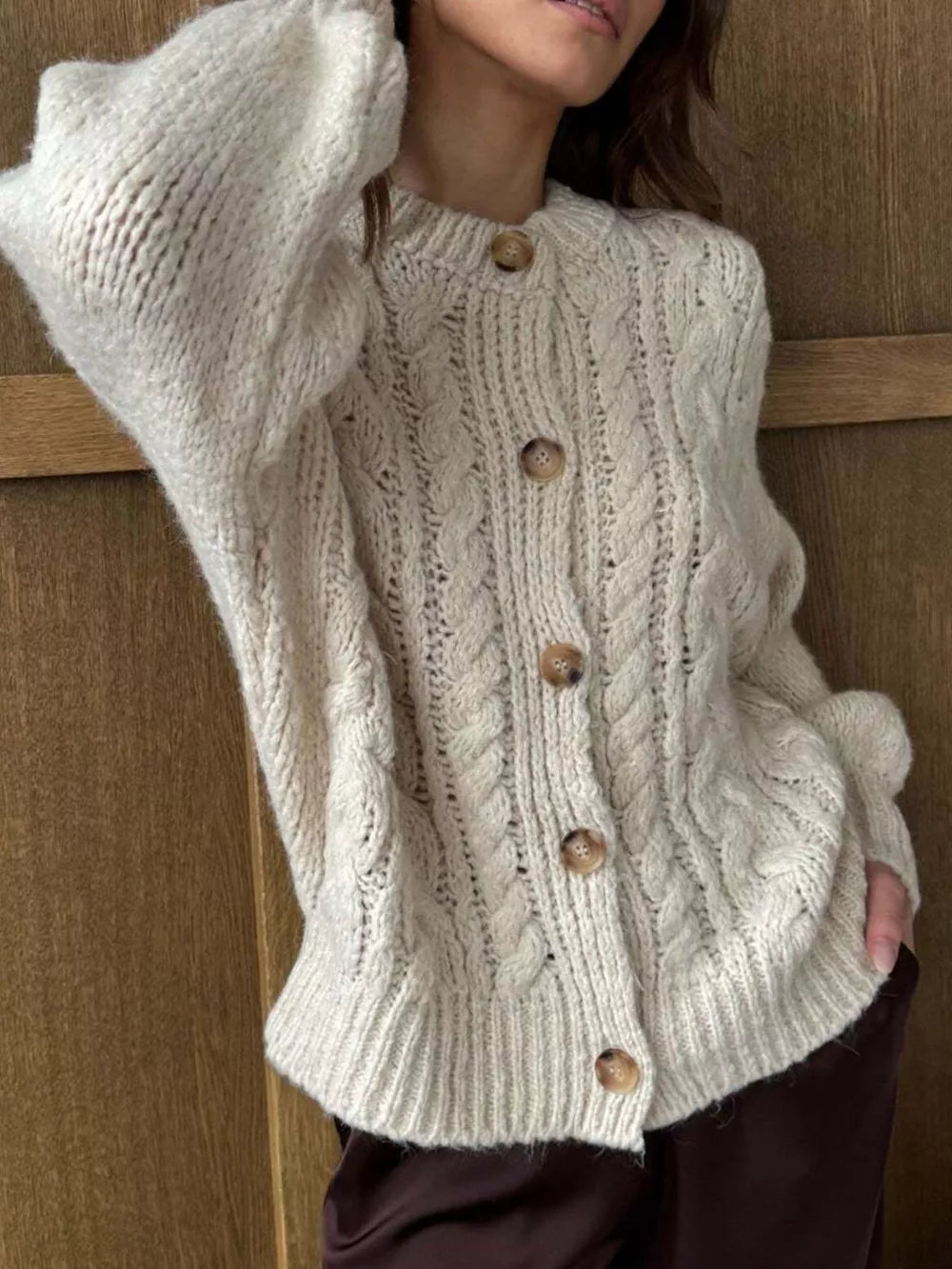 Ivory cable-knit button-down cardigan with wooden buttons and crew neck.
