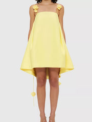 Yellow A-line mini dress with floral applique straps and hem detail.