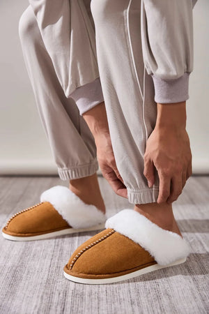 Caramel suede house slides with white shearling trim and decorative stitching.