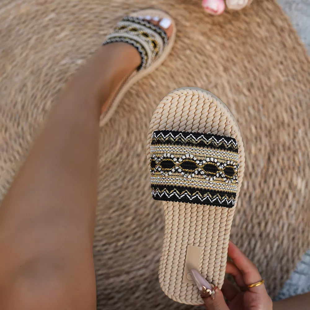 Embossed strap open-toe flat sandals with black and gold beaded detail.