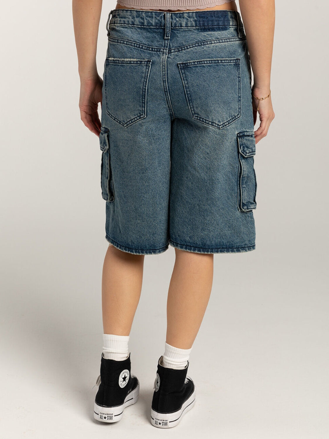 Light blue denim cargo bermuda shorts with buttoned pockets and distressed details.