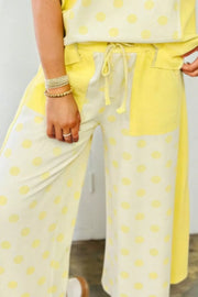 Yellow polka dot cotton blend wide leg pants with drawstring waist and color block detail.