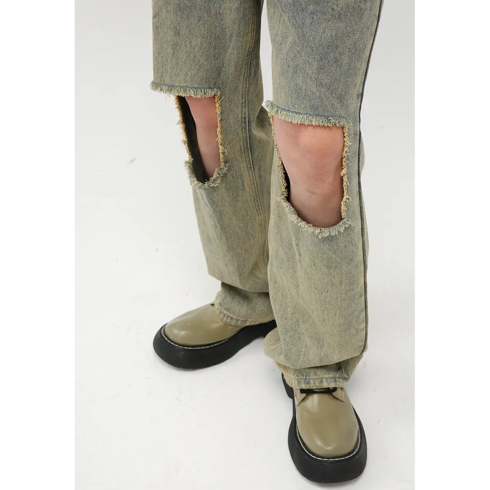 Distressed medium wash denim cargo jeans with cut-outs at the knees and frayed hems.