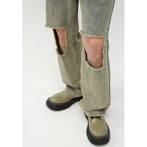 Distressed medium wash denim cargo jeans with cut-outs at the knees and frayed hems.