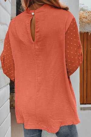 Orange blouson top with textured fabric and Swiss dot sleeves, featuring a keyhole back detail.