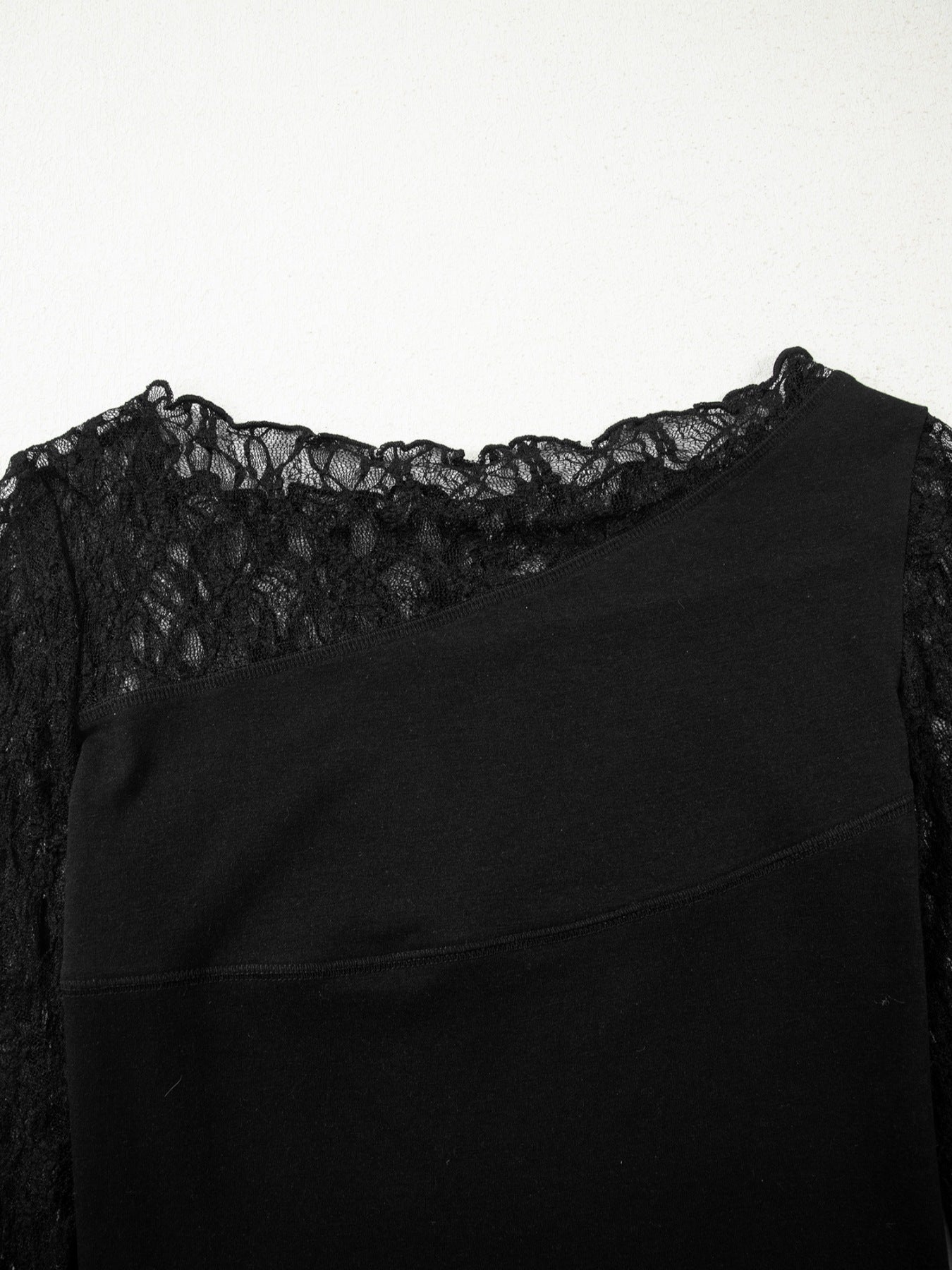 Black asymmetric sheer blouse with lace trim and long sleeves.