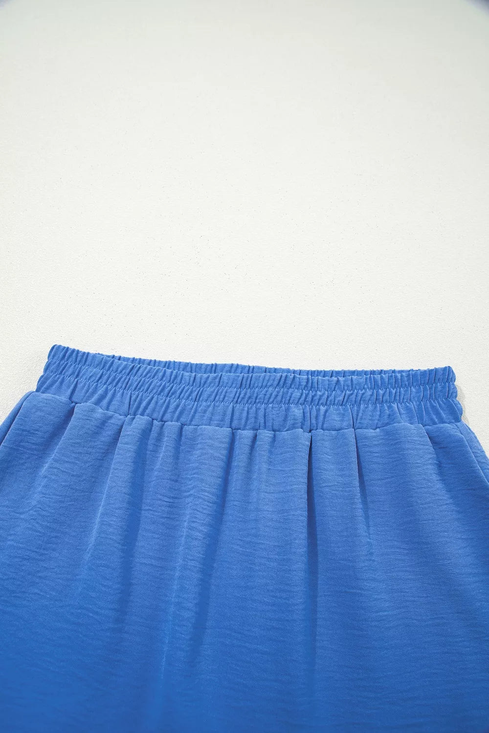 Blue flowing shorts with elastic drawstring waist and textured fabric detail.