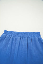 Blue flowing shorts with elastic drawstring waist and textured fabric detail.