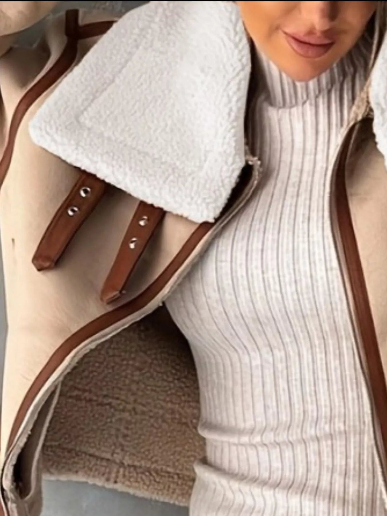 Shearling lined zip up jacket in tan with brown trim and buckle details.