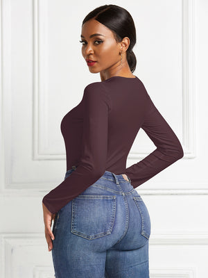 Burgundy long sleeve ribbed jersey bodysuit with a scoop neck, styled with jeans.