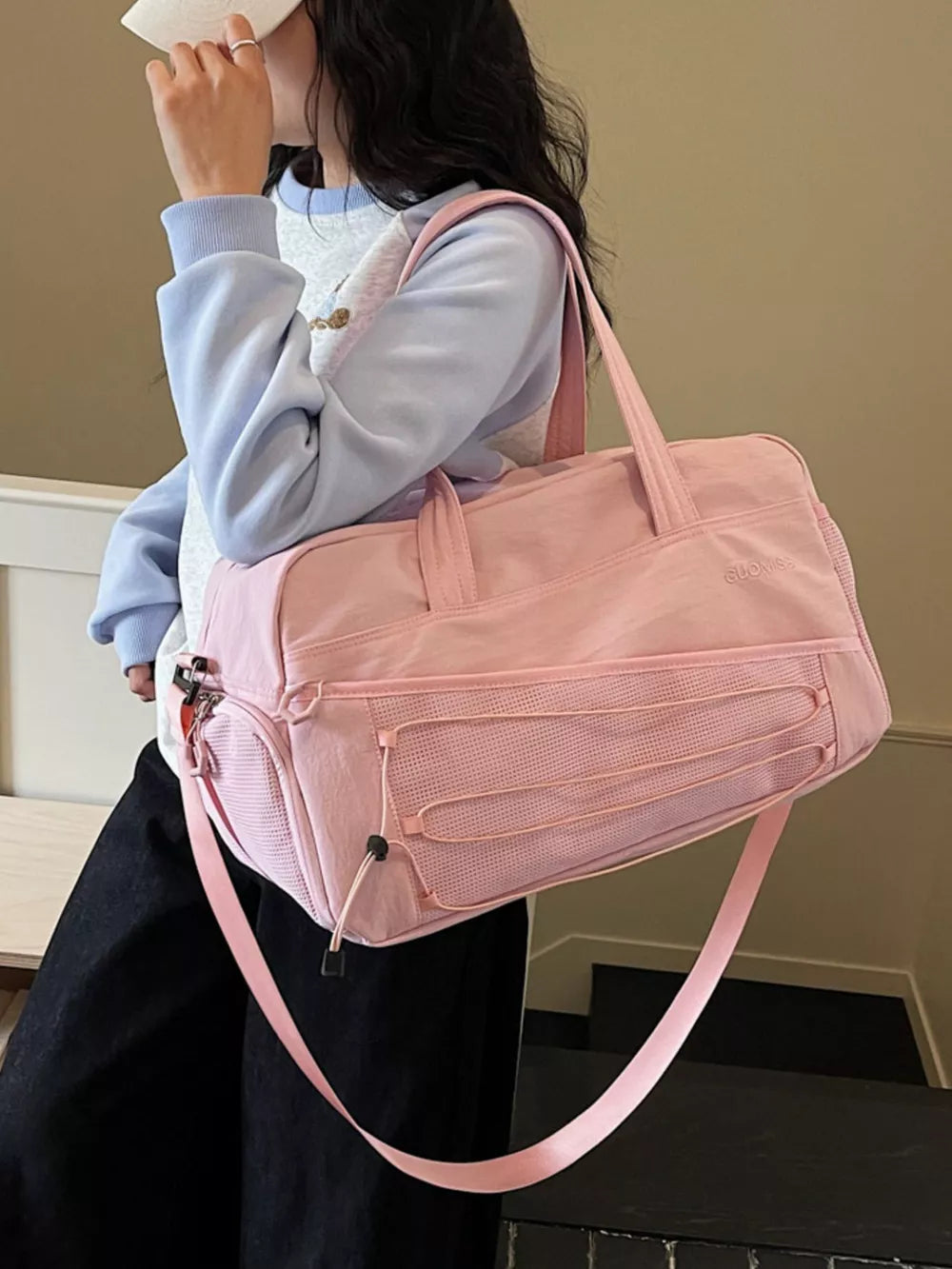 Pink nylon travel organizer bag with adjustable strap and bungee cord details.