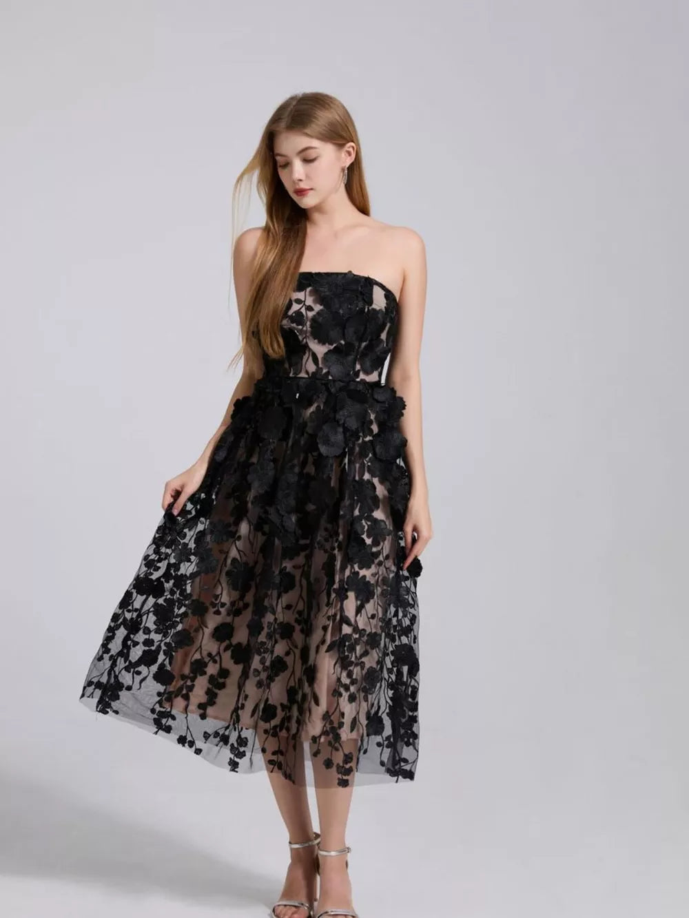 Black strapless midi dress with intricate floral applique and sheer overlay.