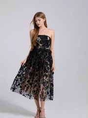 Black strapless midi dress with intricate floral applique and sheer overlay.
