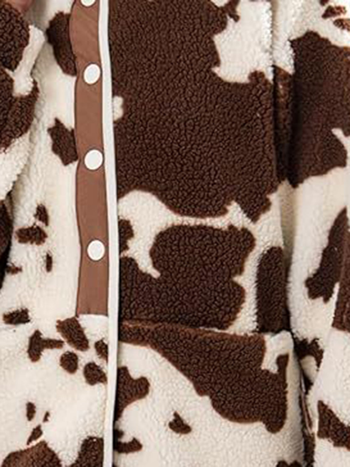 Cow print sherpa button-up jacket with white buttons and brown trim.