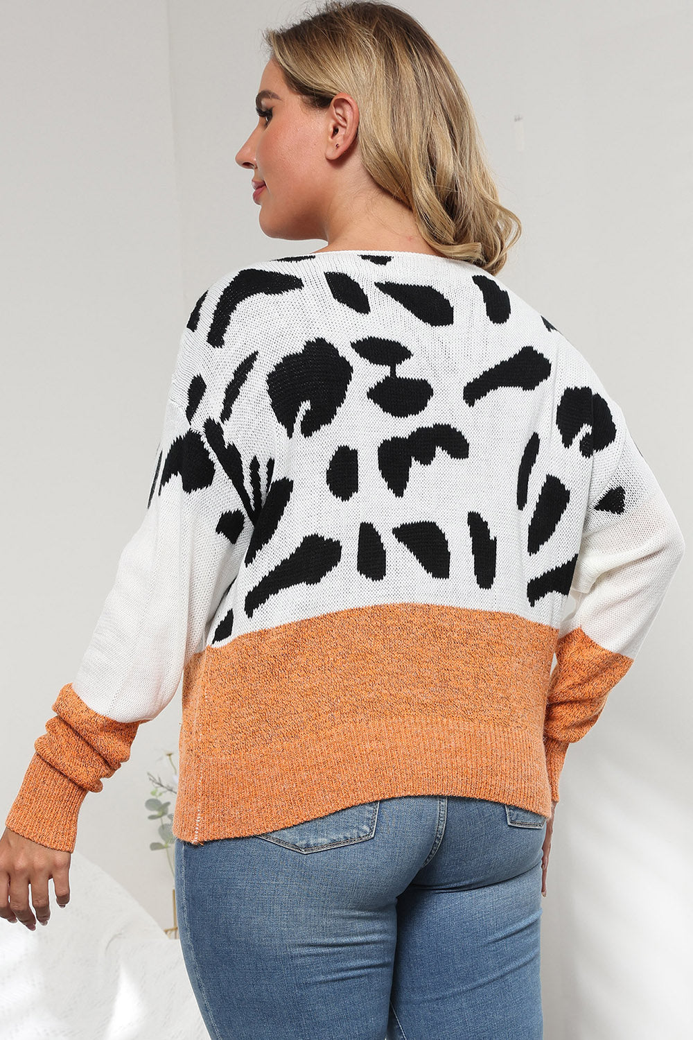Dalmatian print colorblock knit sweater with orange band and white sleeves.