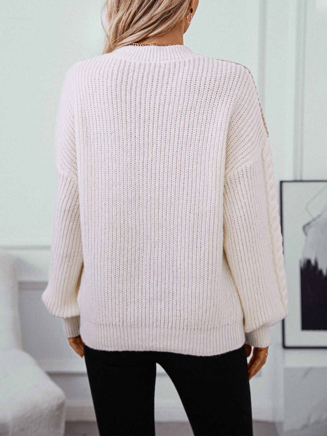 Cream cable knit sweater with textured sleeves and ribbed details.