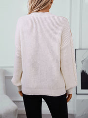 Cream cable knit sweater with textured sleeves and ribbed details.