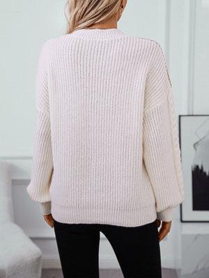 Cream cable knit sweater with textured sleeves and ribbed details.