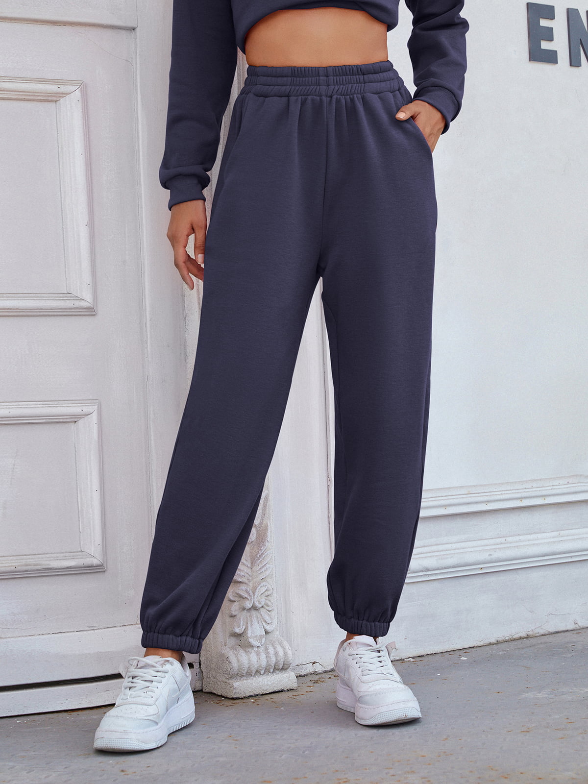 Dark blue relaxed fit joggers with cuffed ankles and pockets, styled with white sneakers.