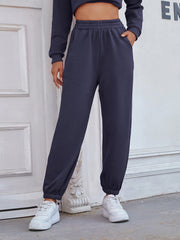 Dark blue relaxed fit joggers with cuffed ankles and pockets, styled with white sneakers.