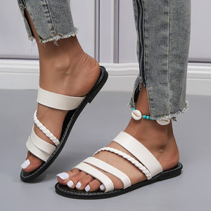 White braided strap open-toe flat sandals with multiple straps and a black sole.