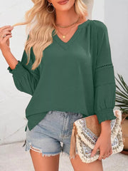 Elegant smocked long sleeve blouse in dark green polyester with v-neck and cinched cuffs.