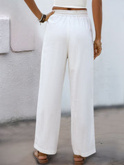 White linen-blend wide-leg trousers with drawstring waist and elastic band detail.