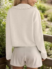Cream knit cardigan with a frilled collar and button front, cropped length.