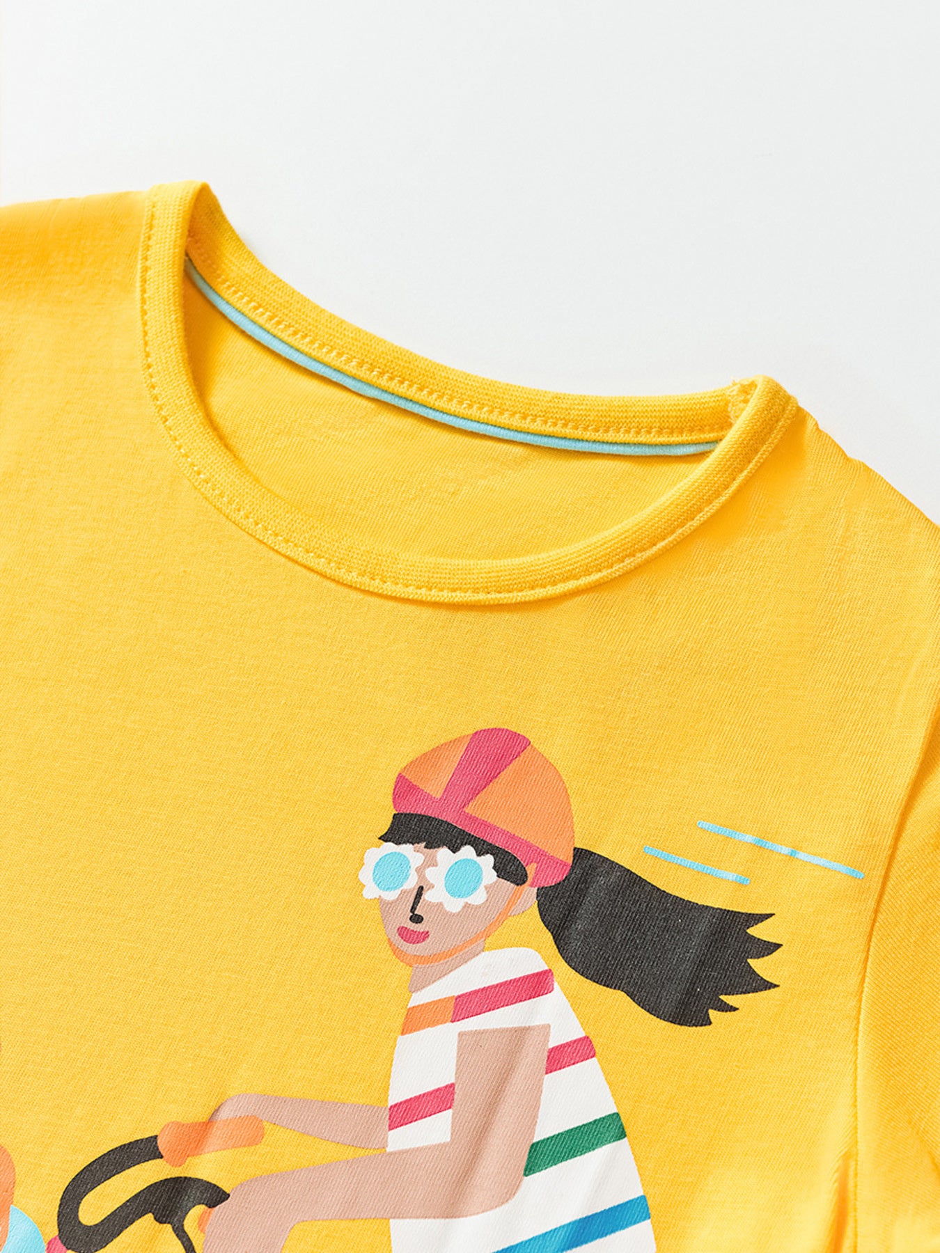 Yellow cotton crew neck t-shirt with a graphic of a girl riding a bicycle.