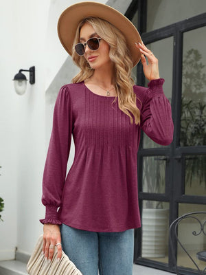 Pleated bodice gathered sleeve top in burnt coral with round neckline and smocked cuffs.