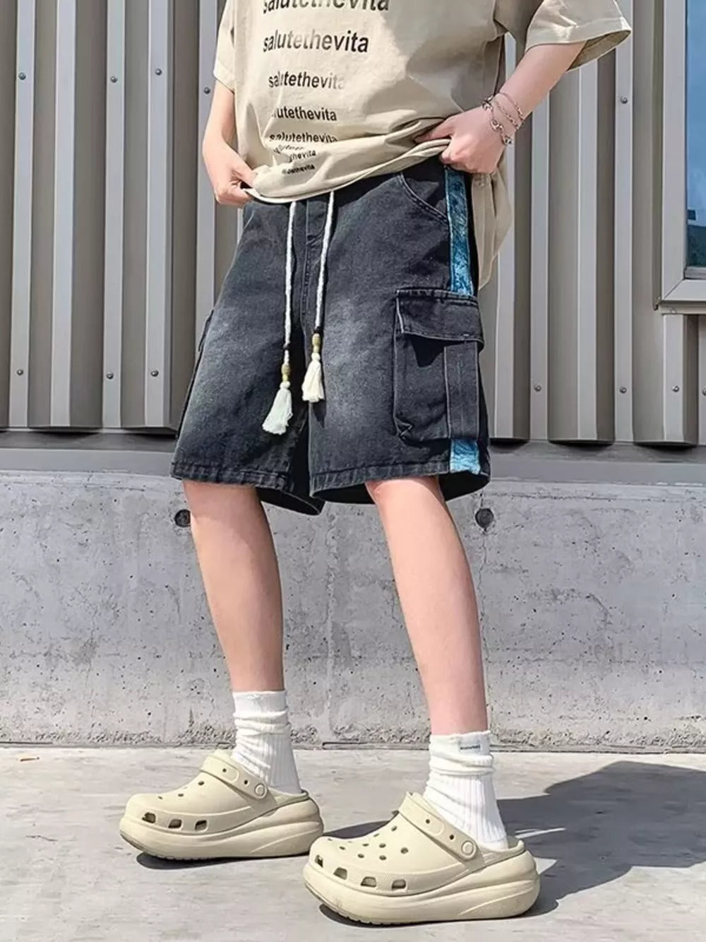 Black denim cargo shorts with braided drawstring and tassel details.