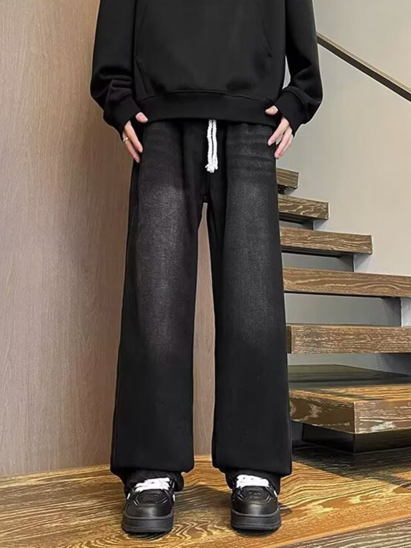 Men's black wide leg jeans with drawstring waist and distressed wash.