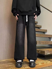 Men's black wide leg jeans with drawstring waist and distressed wash.