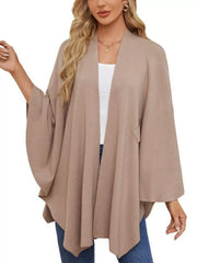 Beige knit cape top with draped elegance and wide sleeves, shown on a model.