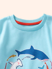 Baby blue cotton t-shirt with playful shark and fish print, crew neck with red trim.
