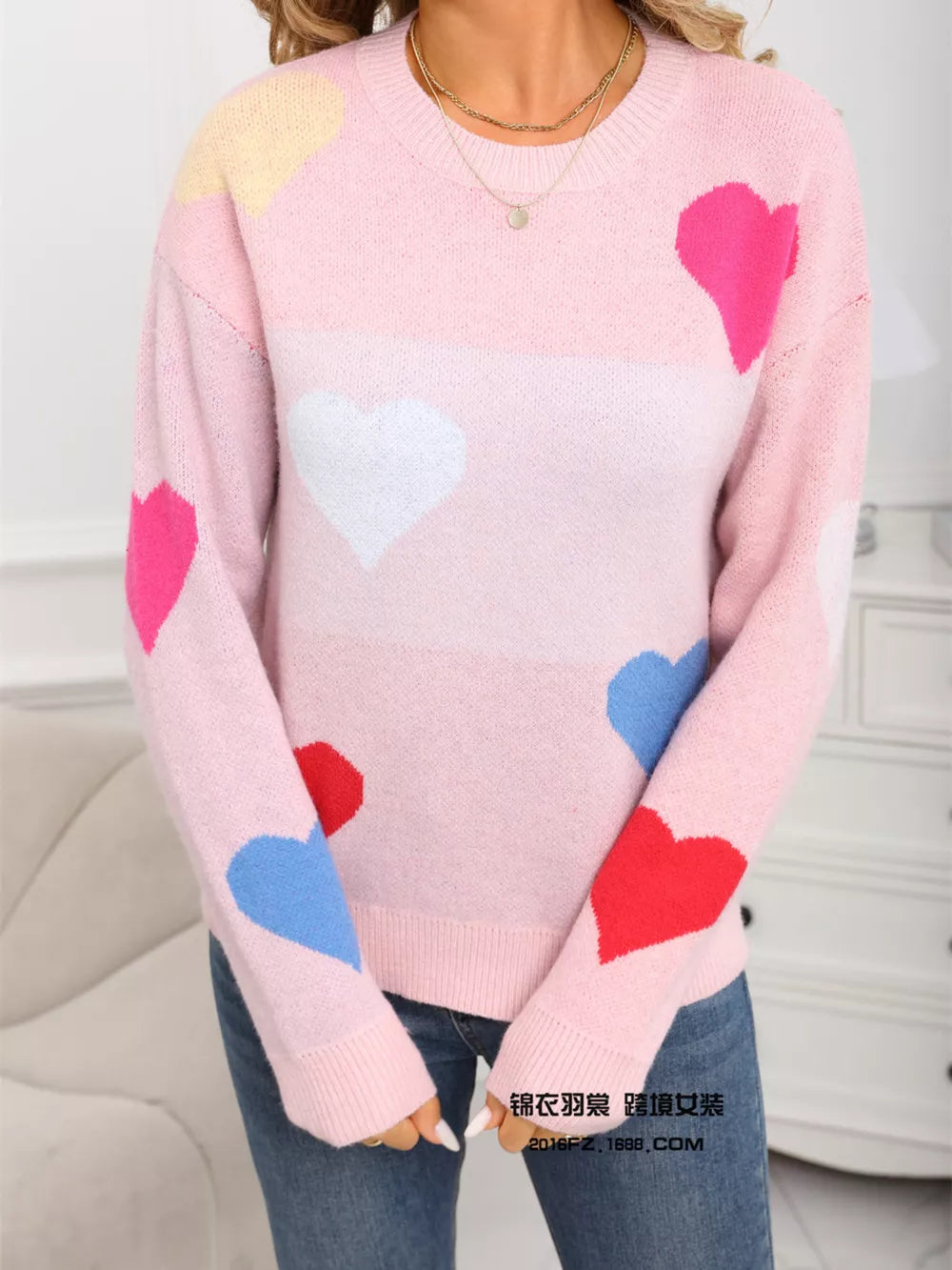 Pink acrylic knit sweater with colorful heart pattern, round neck, long sleeves.