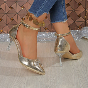 Gold rhinestone bow pointed toe heels with clear heel and ankle strap.