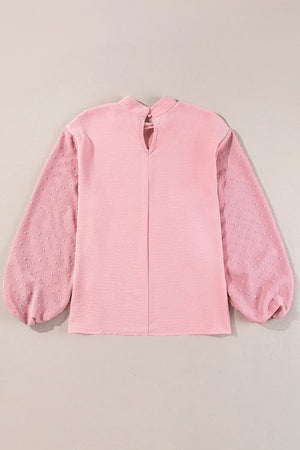 Blush pink blouson top with textured fabric and Swiss dot balloon sleeves.