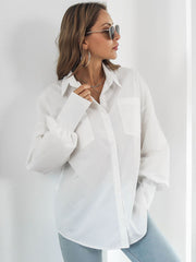 White oversized poplin blouse with blouson sleeves and button front, styled with jeans.