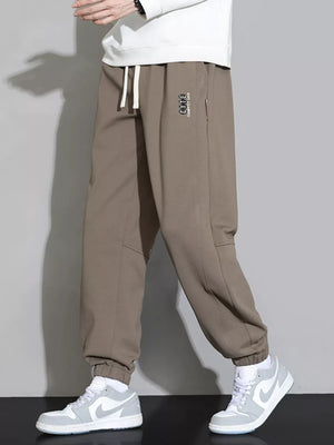 Brown cuffed ankle joggers with drawstring and subtle logo detail.