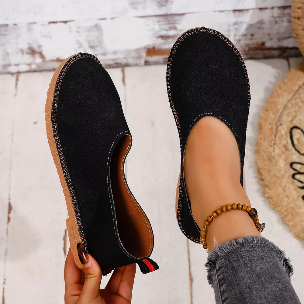 Black espadrille-inspired round toe slip-on flats with contrast stitching and a pull tab.