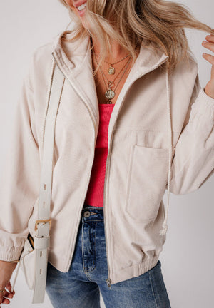 Cream corduroy bomber hoodie with relaxed fit, zip front, drawstring hood, and chest pocket.
